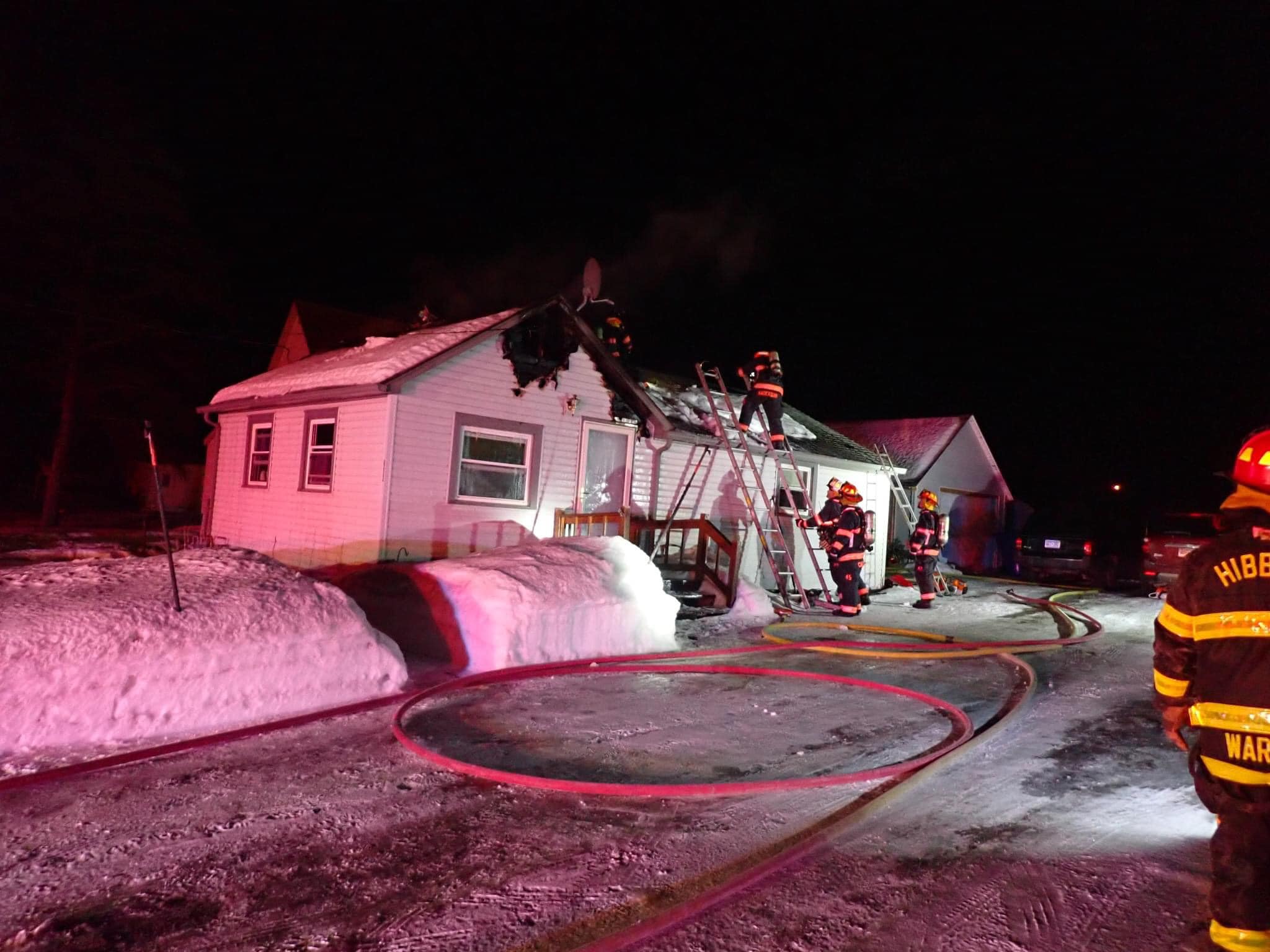 Firefighters operating on top of a roof to suppress the fire.