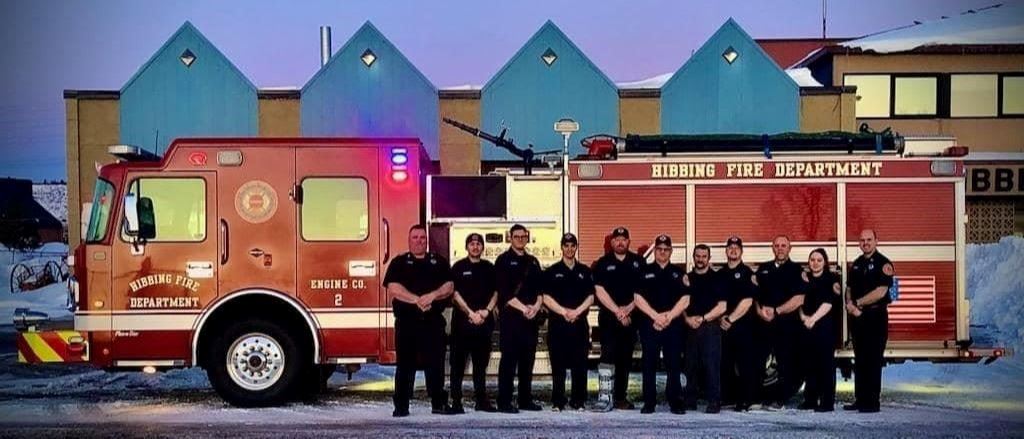 firefighters posing in front of a fire engine