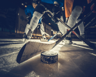 Close up of a hockey puck getting hit by hockey sticks